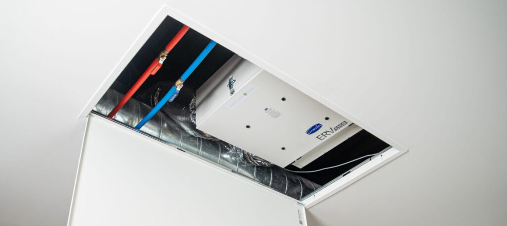 Panneau d’accès HVAC amovible ouvert donnant accès à un module ERV en salle mécanique